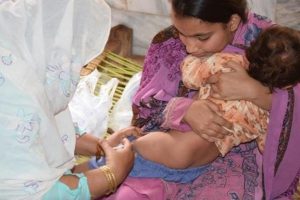 A woman brings her child to the hujra to be vaccinated with IPV during supplementary vaccination activities in Peshawar, Khyber Pakhtunkhwa, Pakistan. WHO/S.Mugha