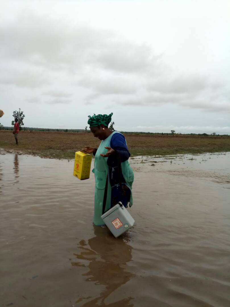 A health worker wades across a shallow river to deliver polio vaccines and other health interventions. © UNICEF Nigeria