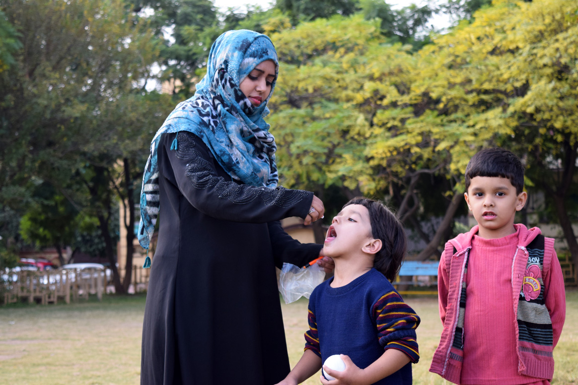 Hafiza administering polio vaccine to a young child in Islamabad, Pakistan. © WHO Pakistan/S.Kashif